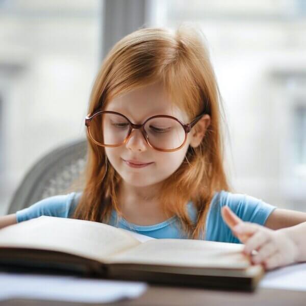 Petite fille rousse qui lit un livre